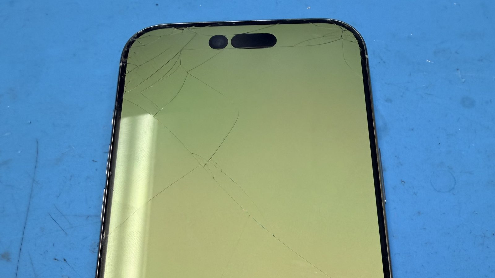 A cracked iPhone front screen with spiderweb damage across the display
