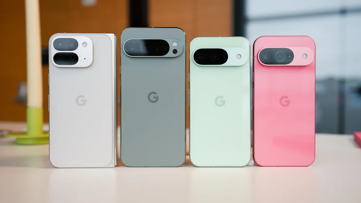 Four Google smartphones stand upright on a table, showcasing their backs in white, gray, mint green, and pink colors, each with a distinctive camera module.